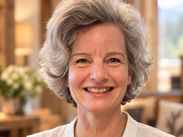 Porträt von Fastenleiterin Birgit Prichzi mit grauen Locken und weißer Leinenbluse in einem gemütlichen Chalet-Ambiente.
